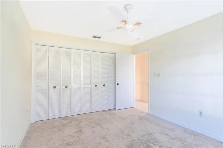 Bedroom with light colored carpet, a closet, and ceiling fan