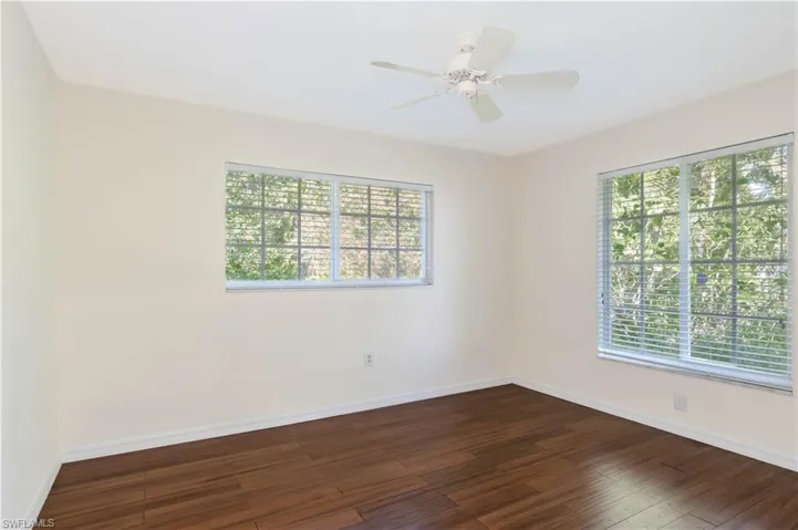 Spare room featuring dark hardwood / wood-style flooring, plenty of natural light, and ceiling fan