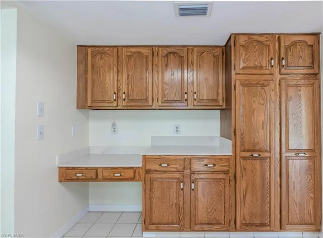 Kitchen featuring light tile patterned floors and built in desk