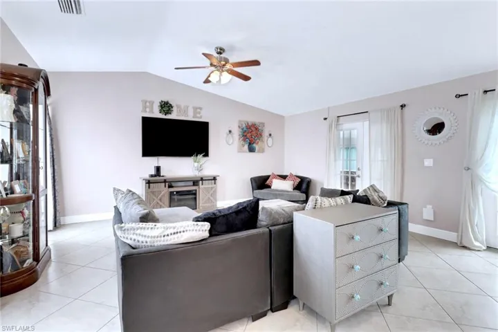 Living area featuring light tile patterned floors, lofted ceiling, and a ceiling fan