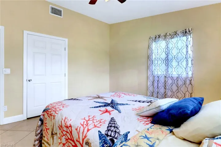 Tiled bedroom featuring a ceiling fan and baseboards