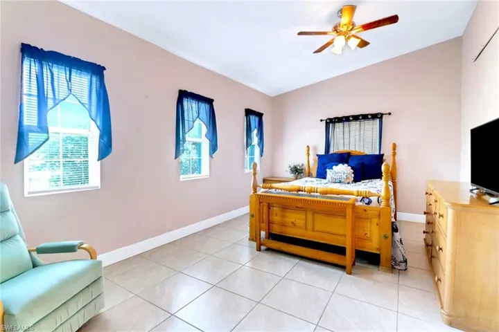 Bedroom with vaulted ceiling, light tile patterned floors, and a ceiling fan