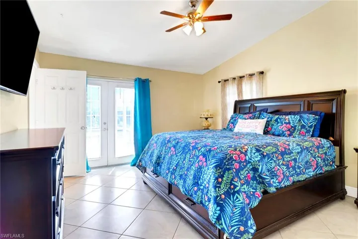 Bedroom featuring french doors, light tile patterned floors, lofted ceiling, access to outside, and ceiling fan