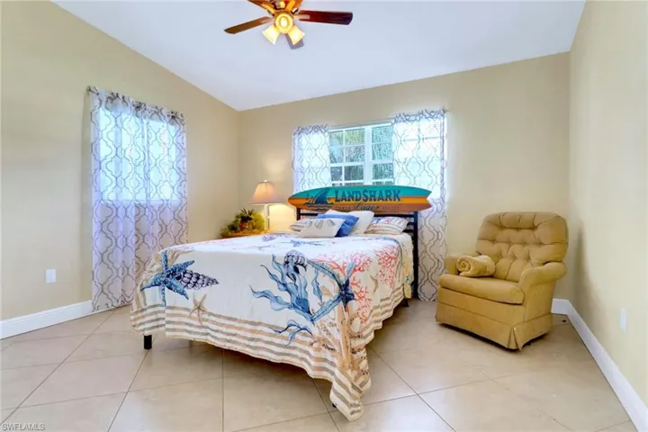 Bedroom with vaulted ceiling, a ceiling fan, and light tile patterned flooring