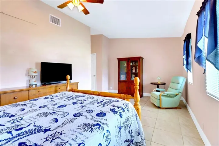 Bedroom featuring light tile patterned flooring, a ceiling fan, and high vaulted ceiling
