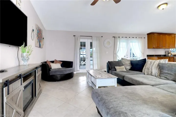 Living room with ceiling fan, light tile patterned floors, and lofted ceiling