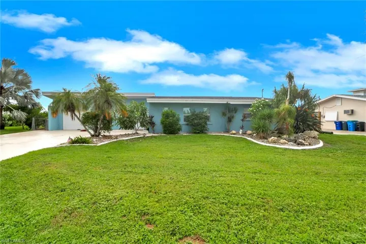 View of front of house with stucco siding, concrete driveway, a front yard, and a garage