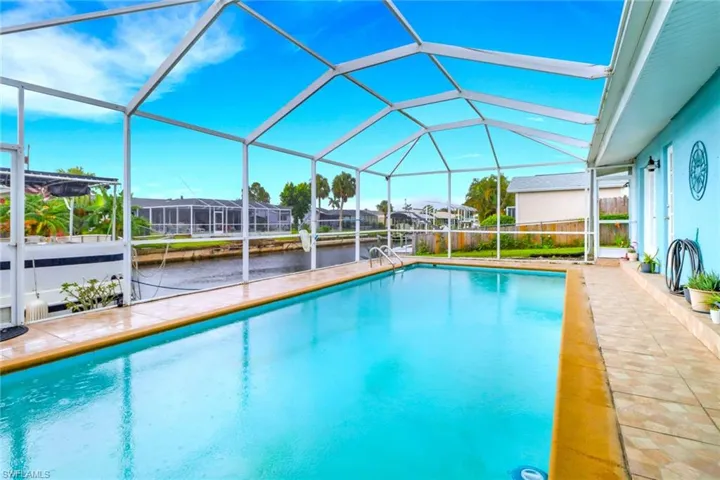 Outdoor pool with a sunroom, a water view, a lanai, and a patio area