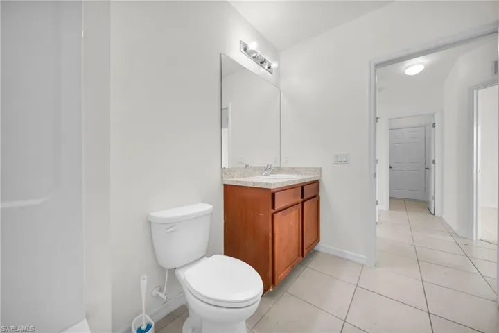 Bathroom featuring a wood-finish vanity with a light-colored countertop, an integrated sink, and a framed mirror with overhead lighting