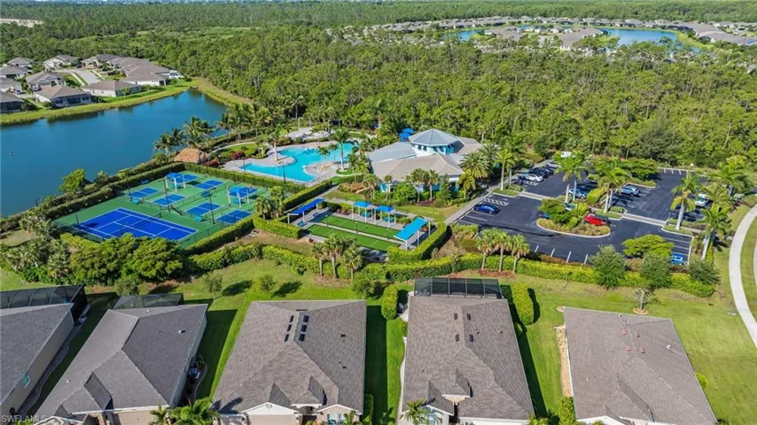 Community amenities featuring multiple pickleball courts, a resort-style swimming pool, a clubhouse building, and a parking area