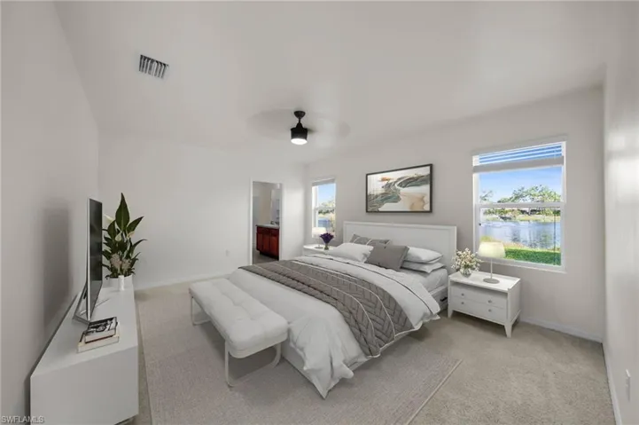Carpeted bedroom featuring multiple windows, a ceiling fan with integrated lighting, and white baseboards.    Virtually Staged