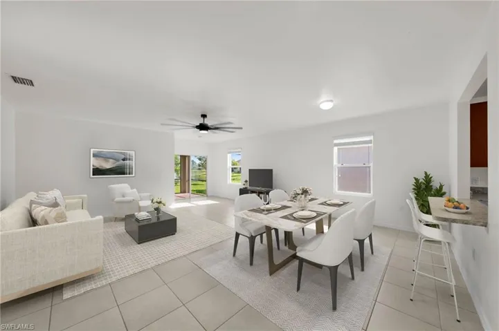 Spacious open-concept living and dining area featuring light-toned tile flooring, a contemporary ceiling fan, and ample natural light from multiple windows and a glass door.    Virtually Staged