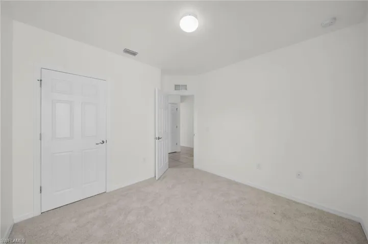 Spacious room featuring light-colored carpeting and white walls