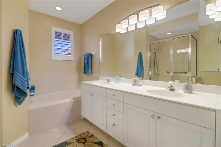Bathroom featuring independent shower and bath, dual bowl vanity, and tile patterned floors