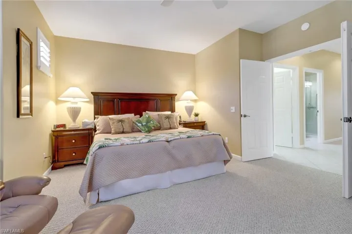 Bedroom featuring ceiling fan, light colored carpet, and ensuite bathroom