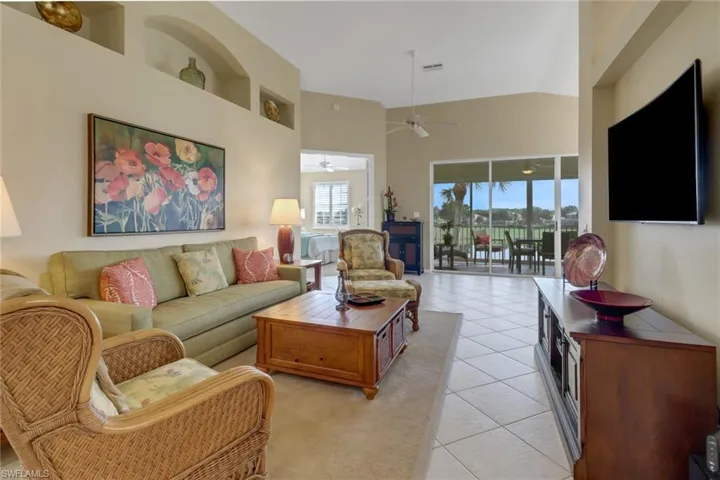 Living room featuring ceiling fan, light tile patterned floors, and vaulted ceiling
