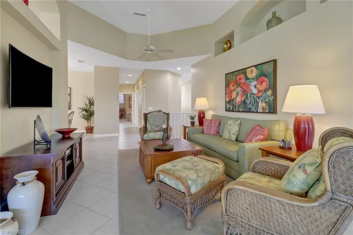 Tiled living room with ceiling fan and a high ceiling