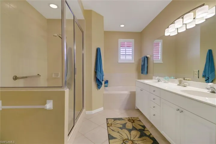 Bathroom with tile patterned flooring, independent shower and bath, and dual bowl vanity