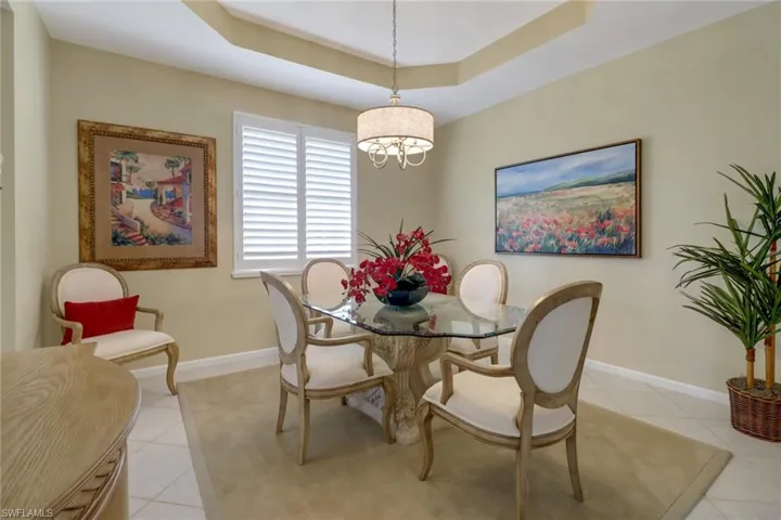 Dining room featuring an inviting chandelier, a tray ceiling, and light tile patterned floors