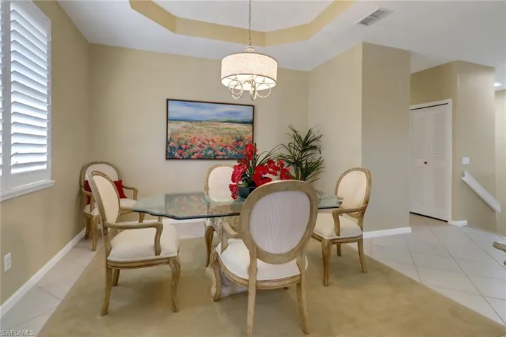 Dining area featuring a raised ceiling, light tile patterned floors, and a chandelier