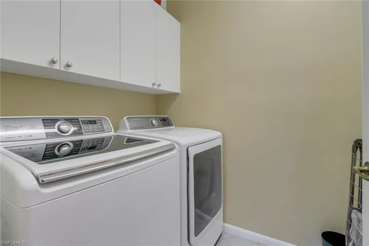 Clothes washing area with light tile patterned flooring, cabinets, and independent washer and dryer