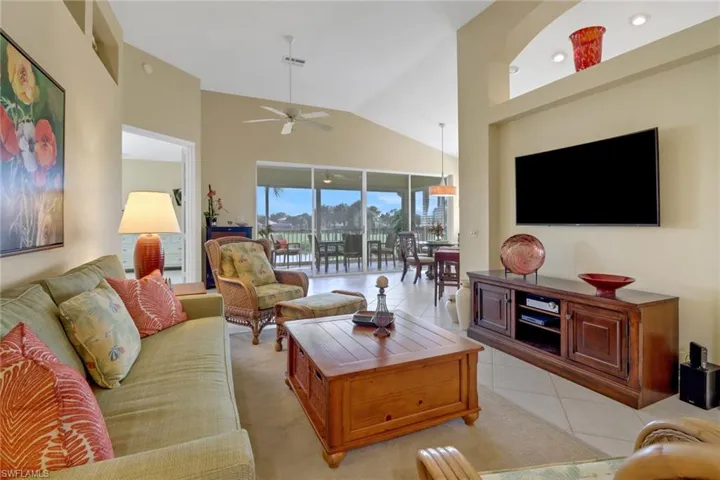 Living room featuring light tile patterned floors, ceiling fan, and lofted ceiling