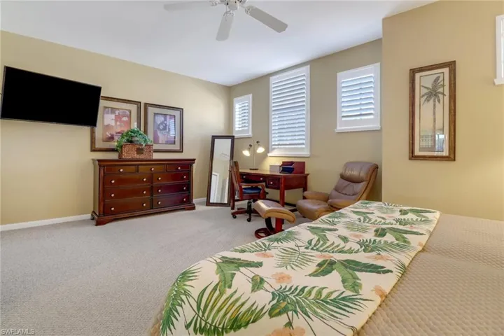 Carpeted bedroom with ceiling fan and multiple windows
