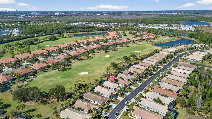 Aerial view of property and surrounding area with a golf club, a nearby body of water, and nearby suburban area