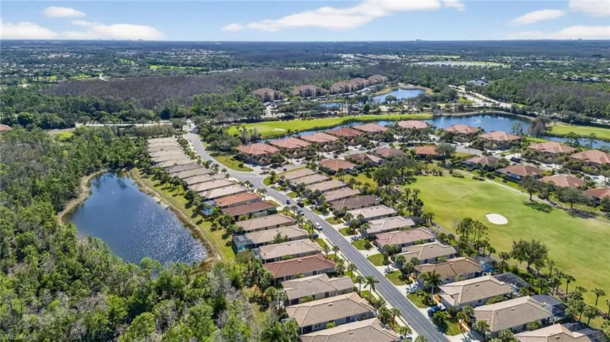 Aerial view of property and surrounding area featuring a large body of water, nearby suburban area, and a golf course