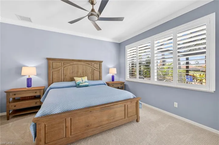 Bedroom with light colored carpet, crown molding, and ceiling fan