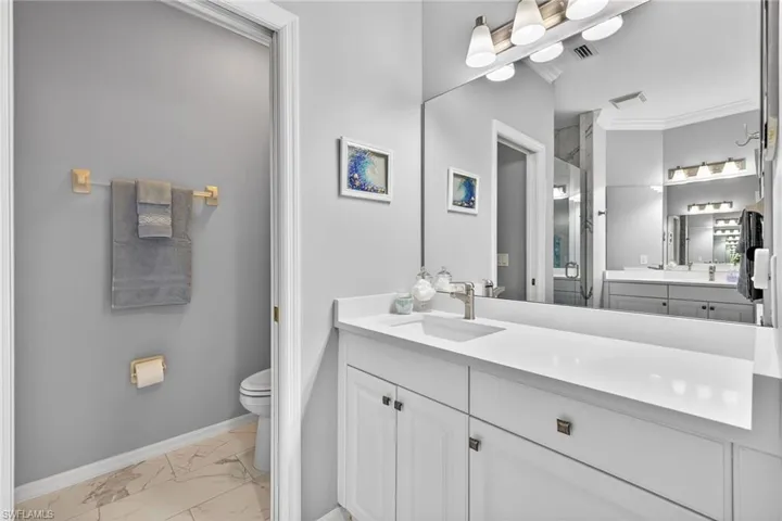 Bathroom featuring vanity, light marble finish floors, and crown molding