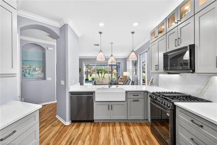 Kitchen featuring black range with gas cooktop, hanging light fixtures, gray cabinetry, stainless steel dishwasher, and light stone countertops