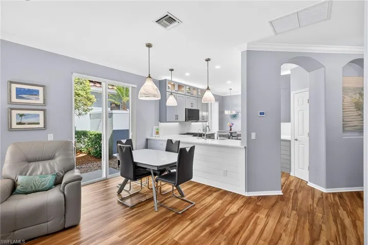 Dining area featuring wood finished floors, crown molding, arched walkways, and recessed lighting