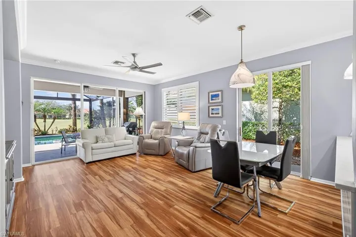 Dining space with ornamental molding, a ceiling fan, and light wood-type flooring