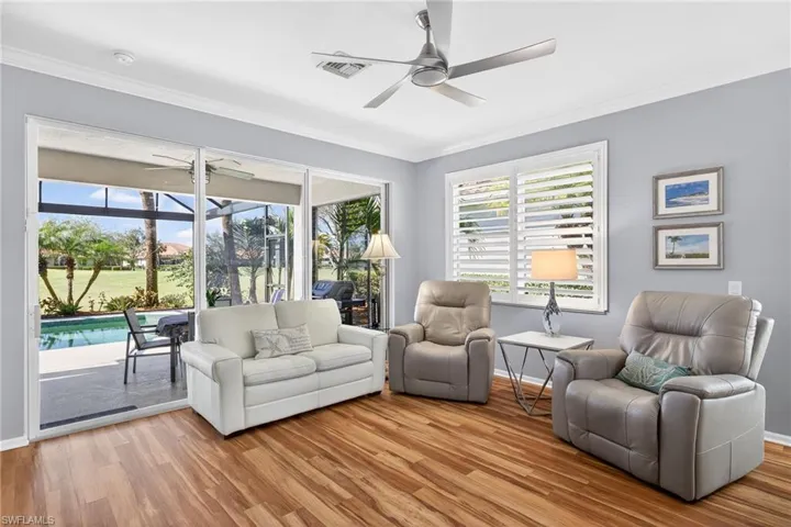 Living room featuring a ceiling fan, light wood-style floors, ornamental molding, and a sunroom