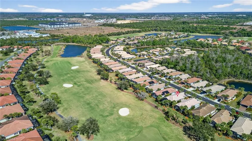 Aerial overview of property's location featuring a large body of water, a golf course, and nearby suburban area