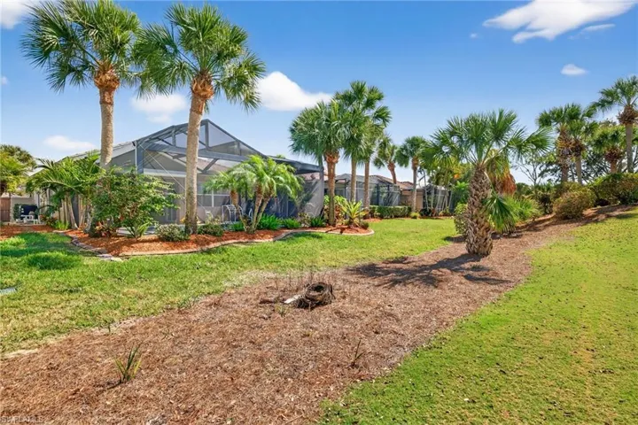 View of grassy yard with a sunroom and a lanai