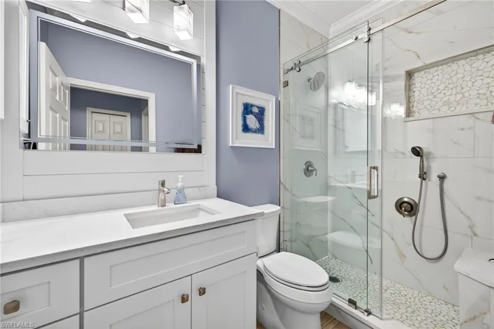 Full bathroom with ornamental molding, a marble finish shower, and vanity