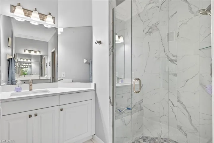 Full bathroom with vanity, a marble finish shower, and crown molding