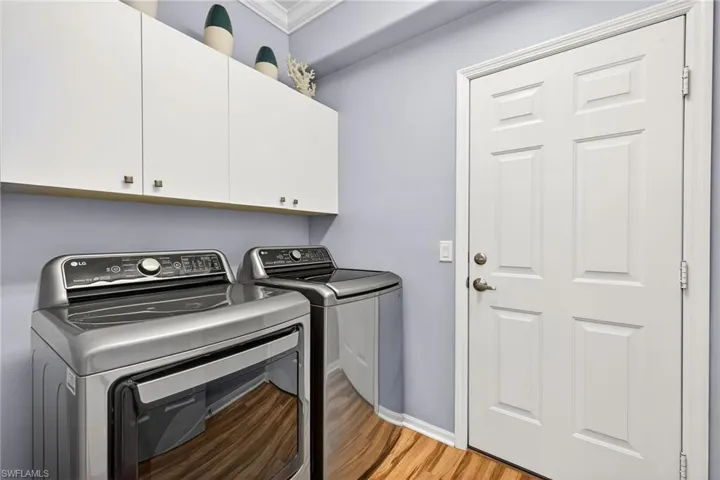 Laundry area featuring cabinet space, light wood-style floors, separate washer and dryer, and crown molding