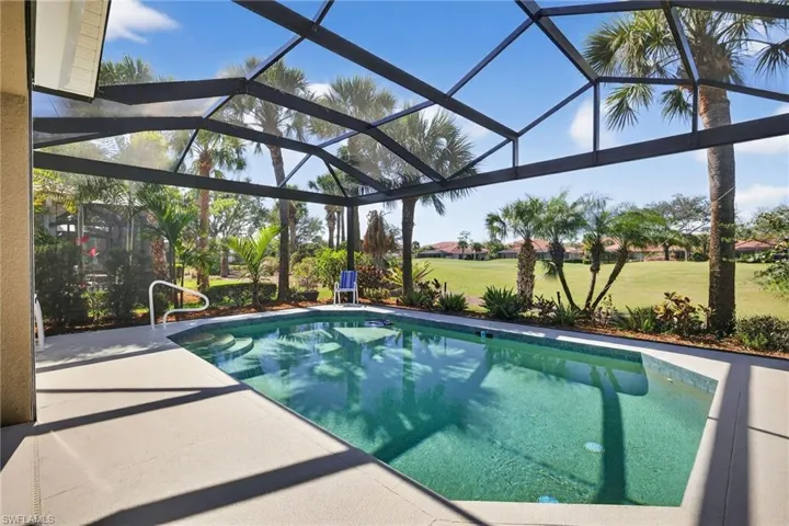 Swimming pool featuring panoramic screen enclosure, view of golf course, a sunroom, and a lawn