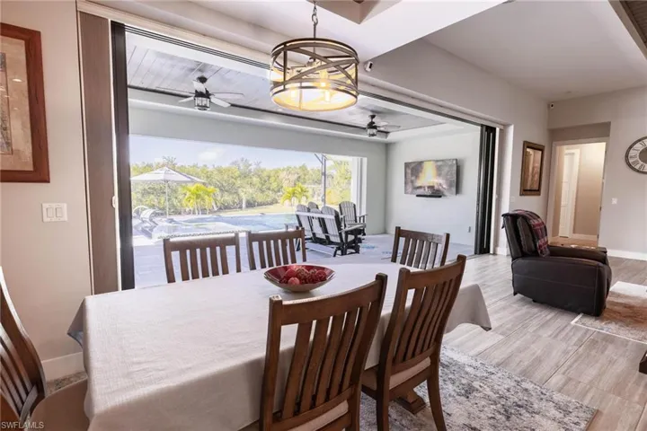 Dining area with light hardwood / wood-style flooring and ceiling fan with notable chandelier