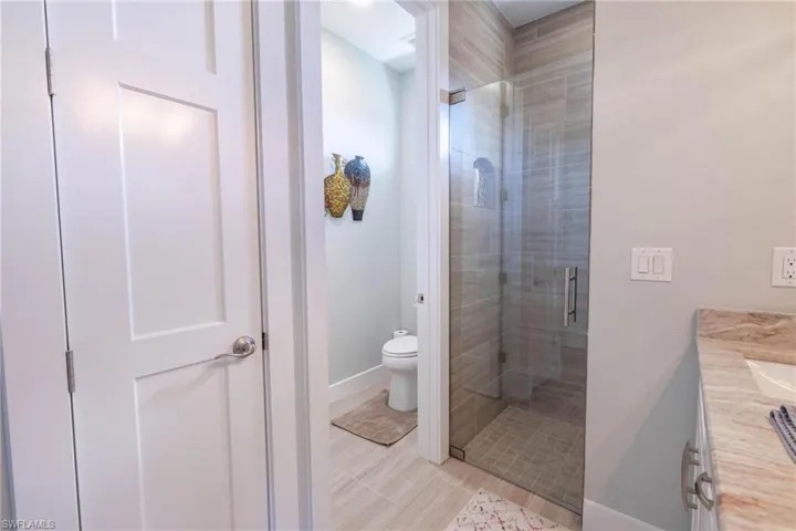 Bathroom with toilet, a shower with shower door, and vanity