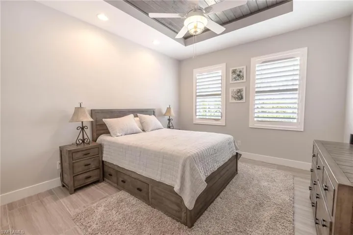 Bedroom featuring ceiling fan, a raised ceiling, and light hardwood / wood-style flooring