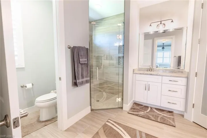 Bathroom featuring a shower with door, toilet, and vanity