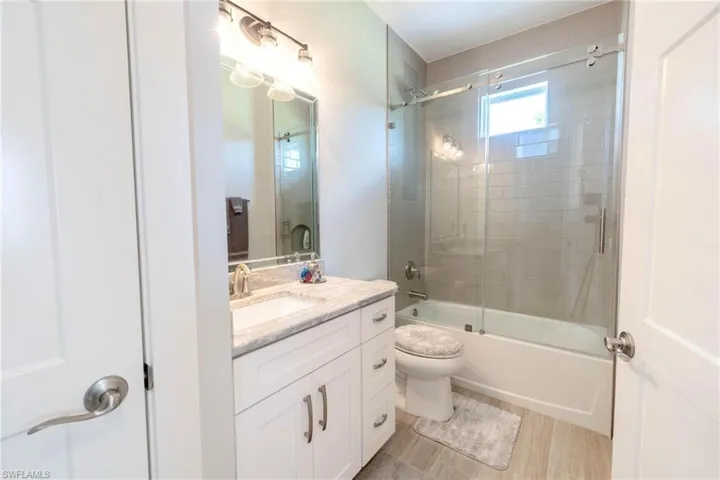 Full bathroom featuring vanity, bath / shower combo with glass door, and toilet
