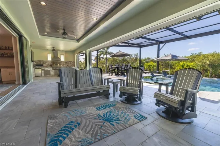 View of patio featuring ceiling fan, glass enclosure, and exterior kitchen