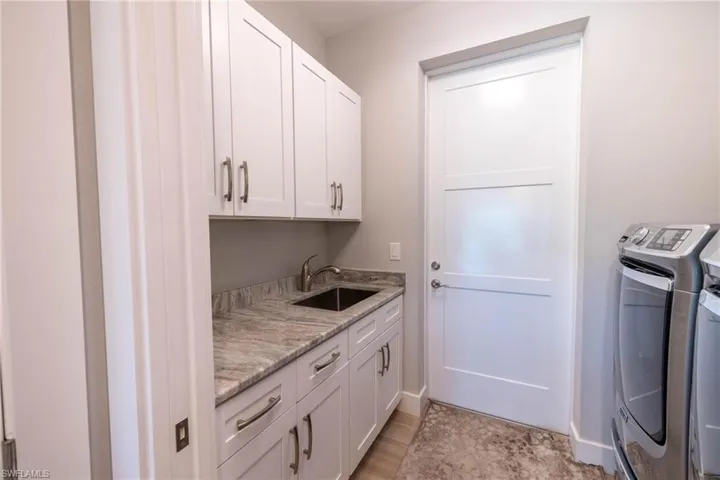 Laundry area featuring light hardwood / wood-style floors, cabinets, sink, and separate washer and dryer