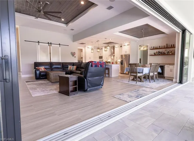 Living room featuring a barn door, a tray ceiling, light wood-type flooring, and ceiling fan
