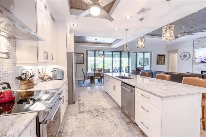 Kitchen featuring white cabinets, stainless steel appliances, and a kitchen island with sink